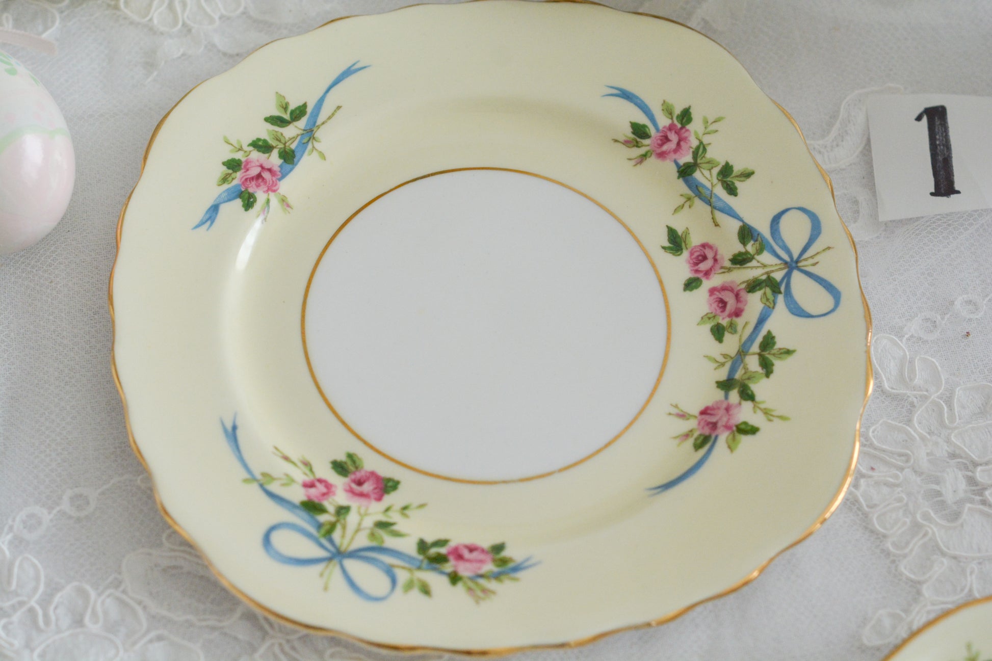 コルクラフ(Colclough)の可愛らしいティートリオ。コルクラフは1890年にハーバード・ジョセフ・コルクラフ氏が創業したメーカで、1940年代頃まで続いていました。コルクラフの中でもこのリボンの絵柄は人気で入手困難なお品です。クリーム色にブルーリボンと小さなバラの模様がとっても可愛らしいデザインです。パステルカラーがイースターや春のティータイムにもぴったりですね!