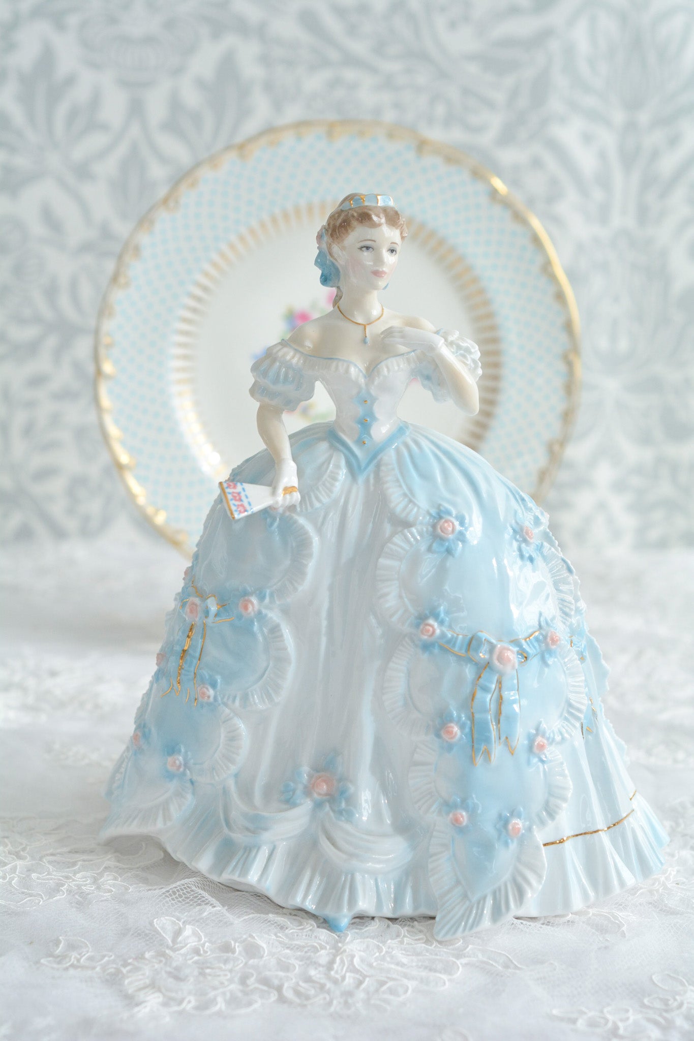 The First Quadrilleという題名のとても可愛らしいロイヤルウースターのフィギュリンです。フィギュリンの題名の通り「初めての舞踏会」に出たご令嬢がモデルになっています。可愛らしいお顔のお嬢様ですが、表情には少し緊張している様子がうまく表現されていると思いませんか?ドレスは爽やかな水色に大きなリボンと薔薇の花がたくさんついていて、舞踏会デビューを華やかに飾っています。とても可愛らしく、美しいフィギュリンでテーブルやお部屋に花を添えてくれます。