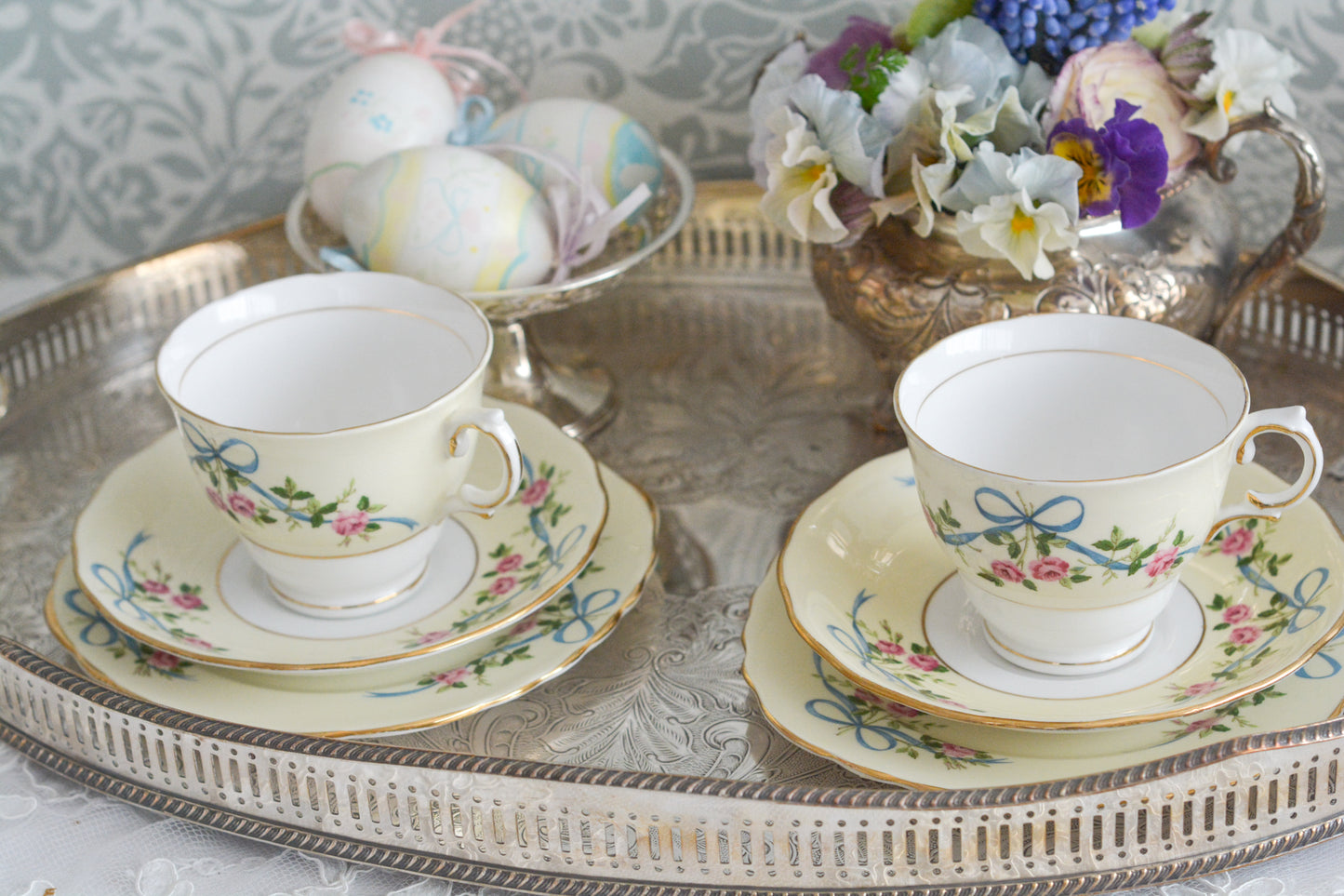 コルクラフ(Colclough)の可愛らしいティートリオ。コルクラフは1890年にハーバード・ジョセフ・コルクラフ氏が創業したメーカで、1940年代頃まで続いていました。コルクラフの中でもこのリボンの絵柄は人気で入手困難なお品です。クリーム色にブルーリボンと小さなバラの模様がとっても可愛らしいデザインです。パステルカラーがイースターや春のティータイムにもぴったりですね!