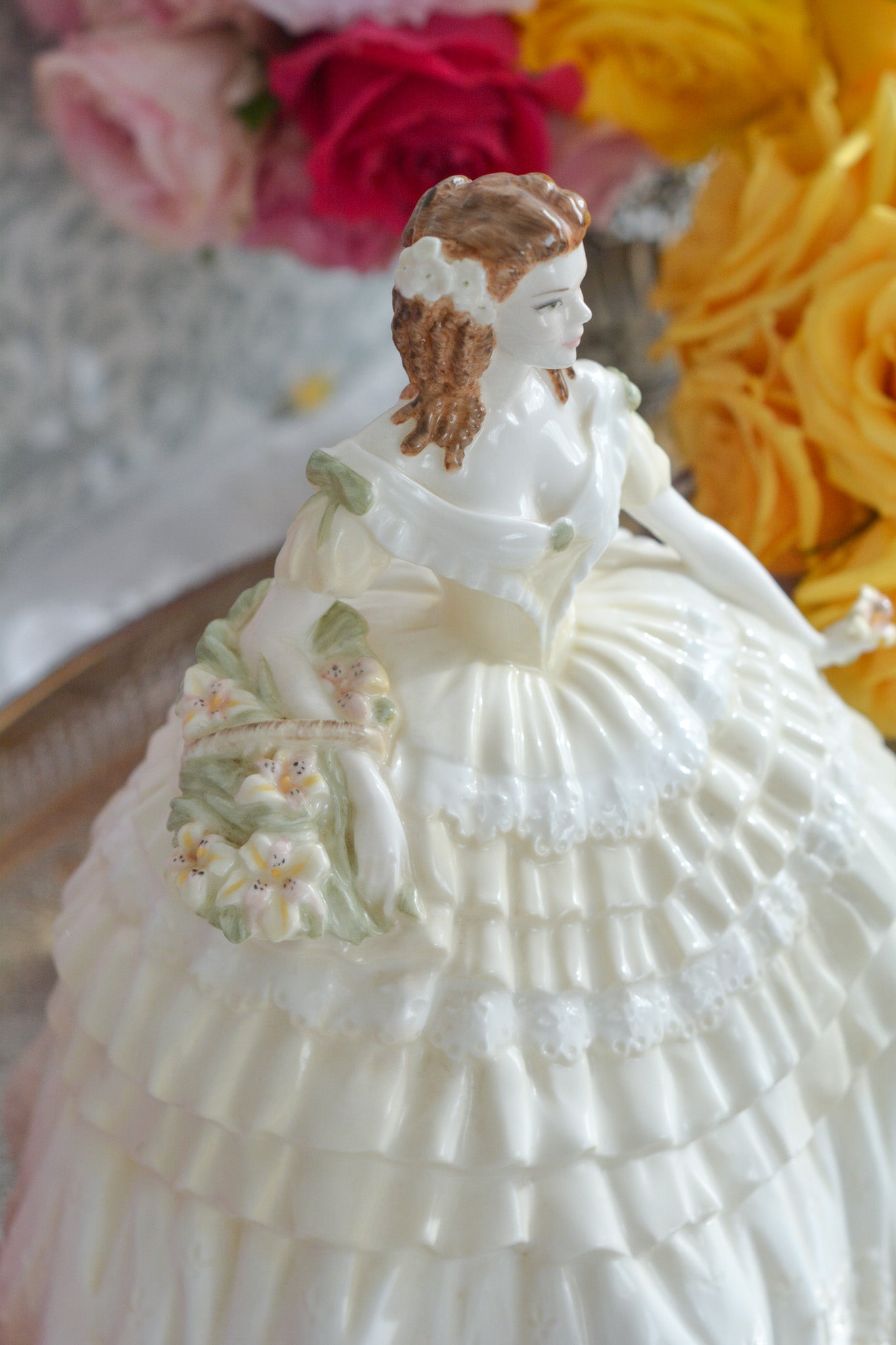 コールポートの人気フィギュリン、「The Four Flowers Collection」。名前の通り、「リリー、ローズ、カーネション、アイリス」の4つのお花がモチーフのフィギュリンシリーズです。 その中でも、リリーはアイリスと並び入手困難なお品です。  バスケットいっぱいのリリーと左手には一輪のリリーの花。ドレスはホワイトに淡いイエローのフリルとグリーンのリボンがあしらわれています。 柔らかな表情がとても可愛らしいレディのフィギュリンです。