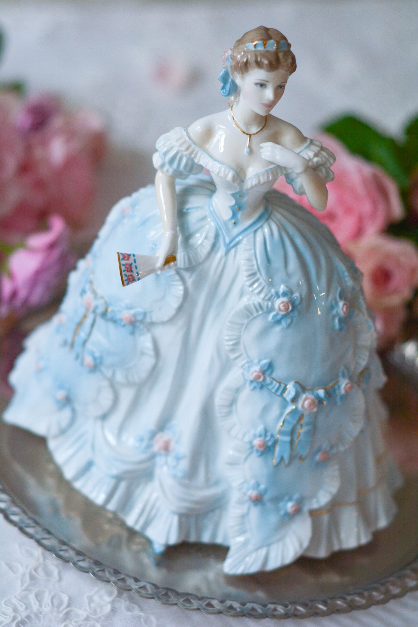 The First Quadrilleという題名のとても可愛らしいロイヤルウースターのフィギュリンです。フィギュリンの題名の通り「初めての舞踏会」に出たご令嬢がモデルになっています。可愛らしいお顔のお嬢様ですが、表情には少し緊張している様子がうまく表現されていると思いませんか?ドレスは爽やかな水色に大きなリボンと薔薇の花がたくさんついていて、舞踏会デビューを華やかに飾っています。とても可愛らしく、美しいフィギュリンでテーブルやお部屋に花を添えてくれます。