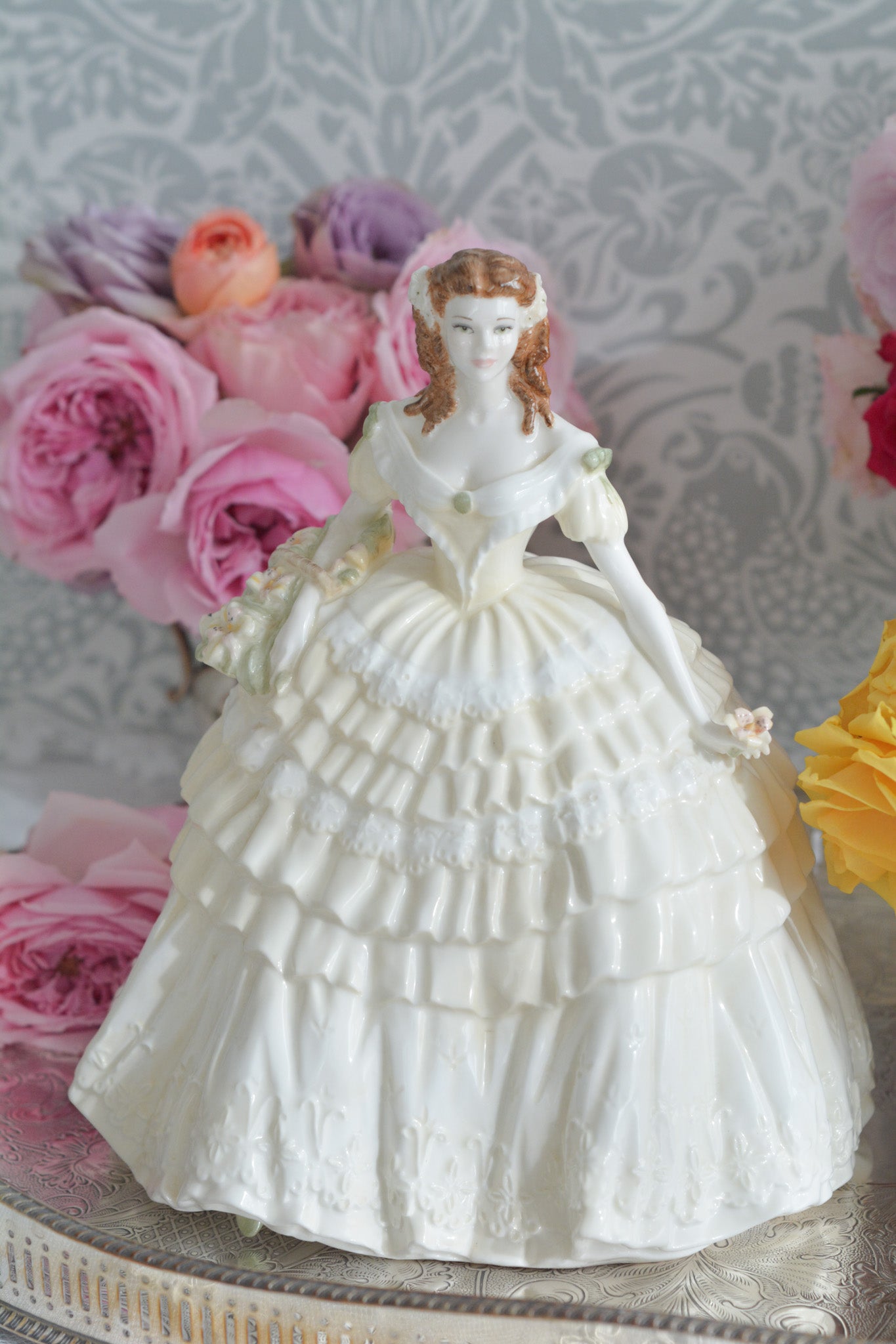 コールポートの人気フィギュリン、「The Four Flowers Collection」。名前の通り、「リリー、ローズ、カーネション、アイリス」の4つのお花がモチーフのフィギュリンシリーズです。 その中でも、リリーはアイリスと並び入手困難なお品です。  バスケットいっぱいのリリーと左手には一輪のリリーの花。ドレスはホワイトに淡いイエローのフリルとグリーンのリボンがあしらわれています。 柔らかな表情がとても可愛らしいレディのフィギュリンです。