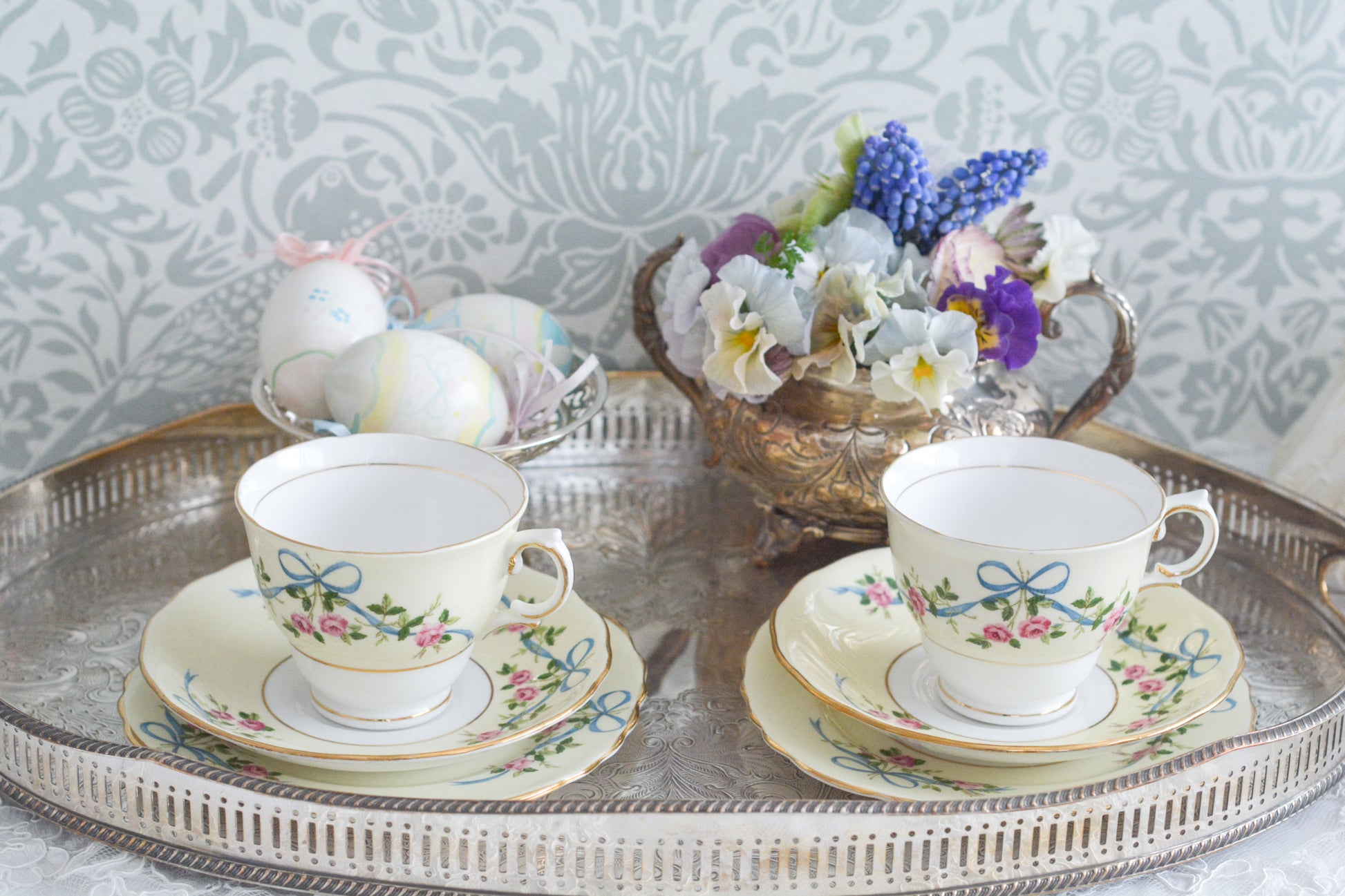 コルクラフ(Colclough)の可愛らしいティートリオ。コルクラフは1890年にハーバード・ジョセフ・コルクラフ氏が創業したメーカで、1940年代頃まで続いていました。コルクラフの中でもこのリボンの絵柄は人気で入手困難なお品です。クリーム色にブルーリボンと小さなバラの模様がとっても可愛らしいデザインです。パステルカラーがイースターや春のティータイムにもぴったりですね!