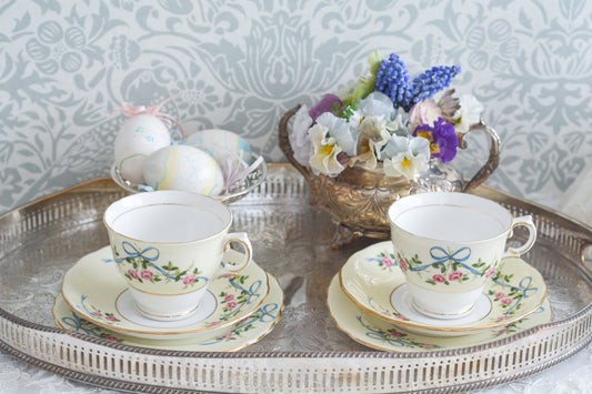 コルクラフ(Colclough)の可愛らしいティートリオ。コルクラフは1890年にハーバード・ジョセフ・コルクラフ氏が創業したメーカで、1940年代頃まで続いていました。コルクラフの中でもこのリボンの絵柄は人気で入手困難なお品です。クリーム色にブルーリボンと小さなバラの模様がとっても可愛らしいデザインです。パステルカラーがイースターや春のティータイムにもぴったりですね!