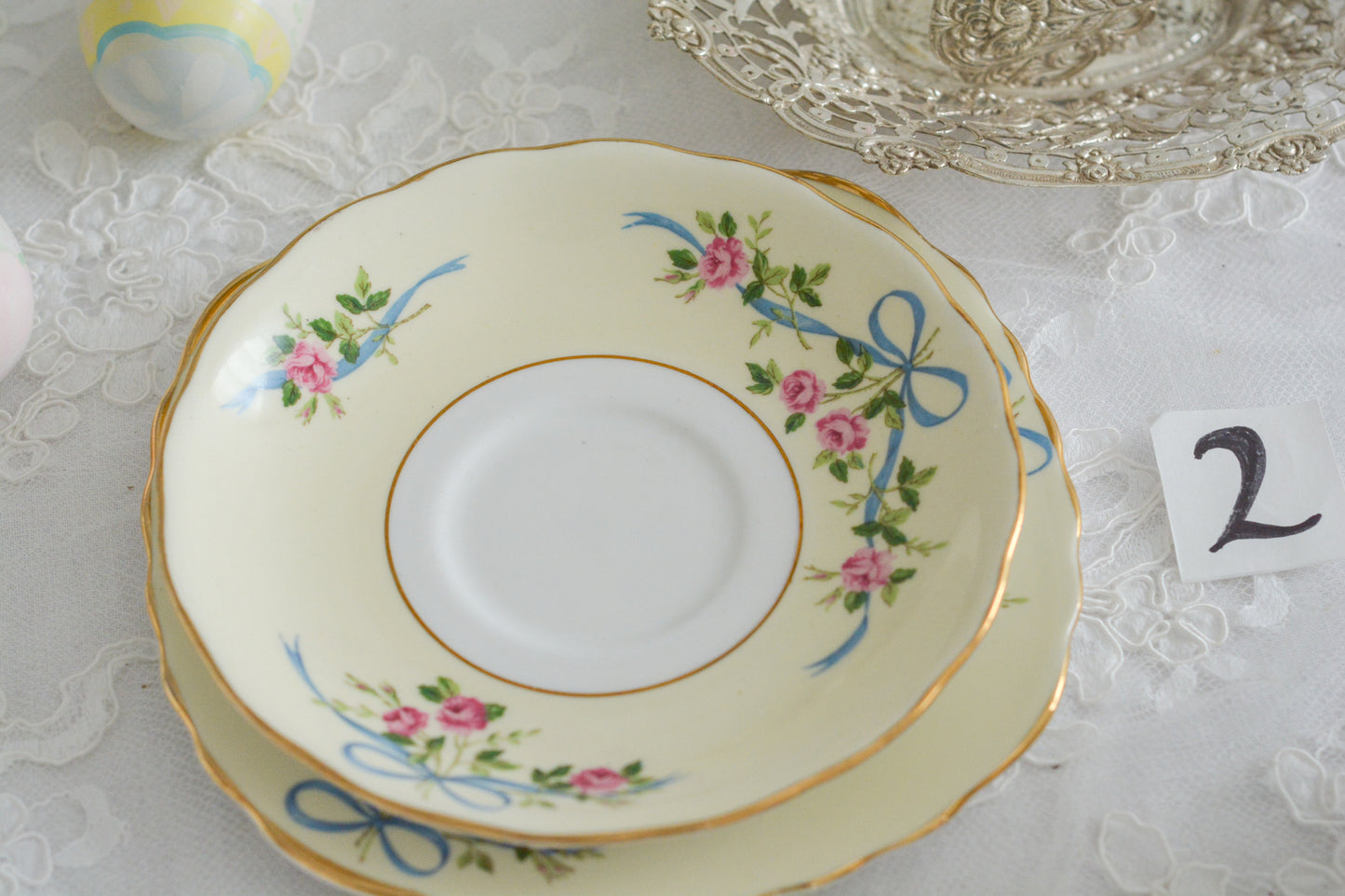 コルクラフ(Colclough)の可愛らしいティートリオ。コルクラフは1890年にハーバード・ジョセフ・コルクラフ氏が創業したメーカで、1940年代頃まで続いていました。コルクラフの中でもこのリボンの絵柄は人気で入手困難なお品です。クリーム色にブルーリボンと小さなバラの模様がとっても可愛らしいデザインです。パステルカラーがイースターや春のティータイムにもぴったりですね!