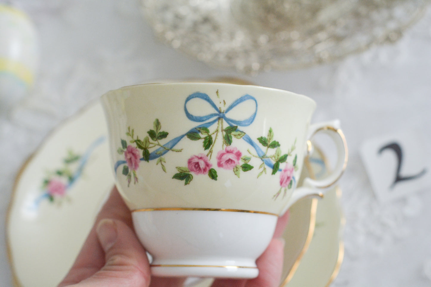 コルクラフ(Colclough)の可愛らしいティートリオ。コルクラフは1890年にハーバード・ジョセフ・コルクラフ氏が創業したメーカで、1940年代頃まで続いていました。コルクラフの中でもこのリボンの絵柄は人気で入手困難なお品です。クリーム色にブルーリボンと小さなバラの模様がとっても可愛らしいデザインです。パステルカラーがイースターや春のティータイムにもぴったりですね!