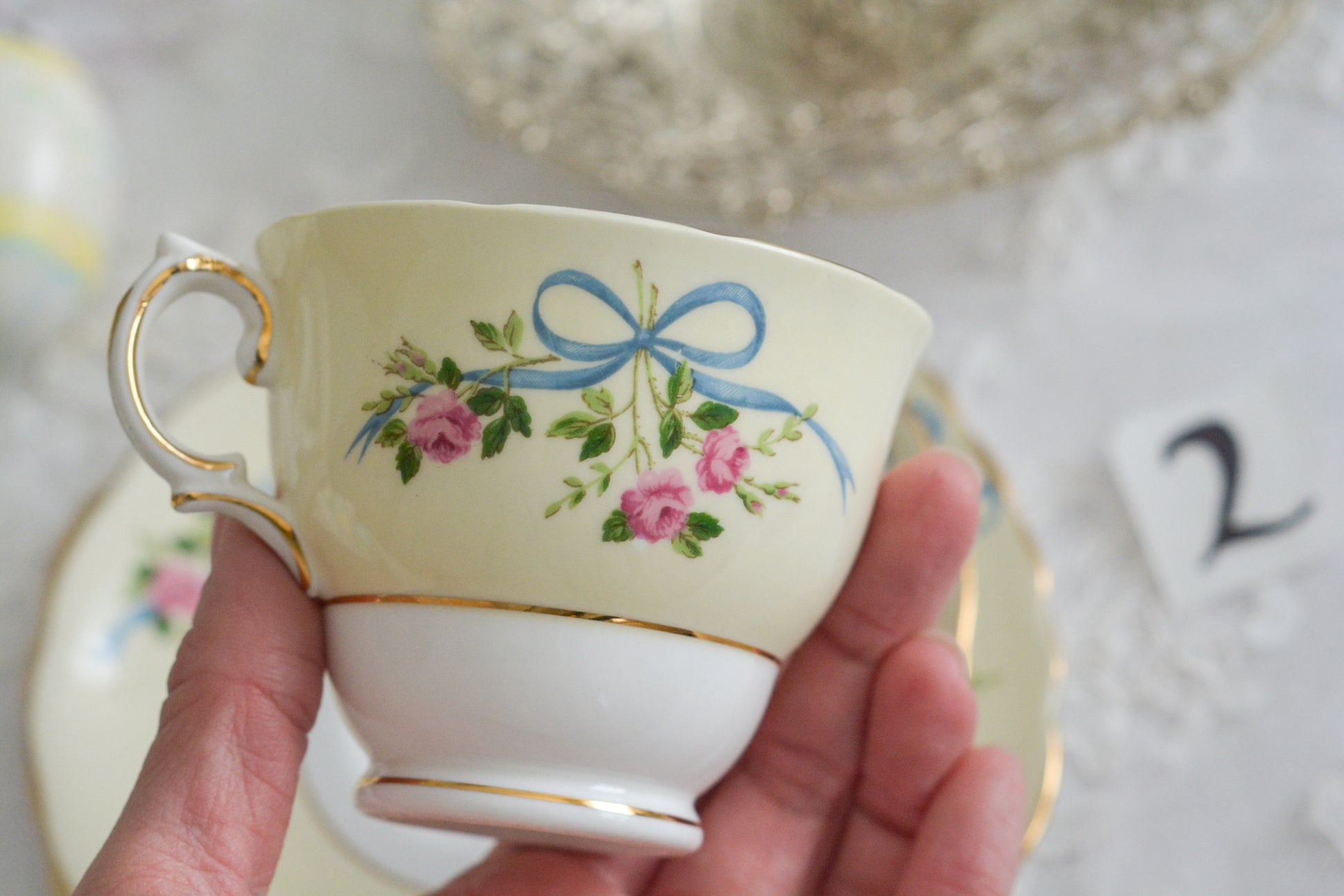 コルクラフ(Colclough)の可愛らしいティートリオ。コルクラフは1890年にハーバード・ジョセフ・コルクラフ氏が創業したメーカで、1940年代頃まで続いていました。コルクラフの中でもこのリボンの絵柄は人気で入手困難なお品です。クリーム色にブルーリボンと小さなバラの模様がとっても可愛らしいデザインです。パステルカラーがイースターや春のティータイムにもぴったりですね!