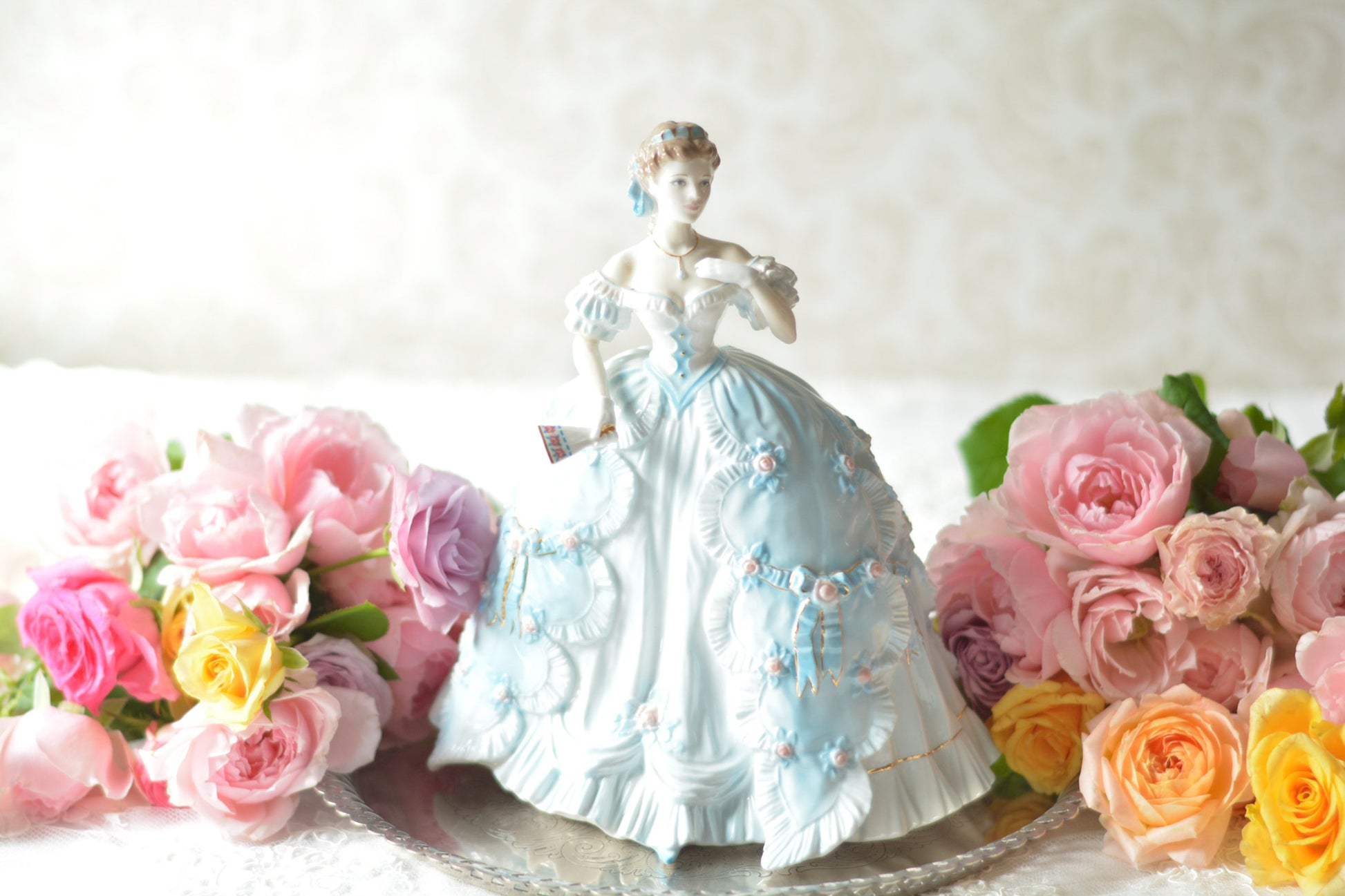 The First Quadrilleという題名のとても可愛らしいロイヤルウースターのフィギュリンです。フィギュリンの題名の通り「初めての舞踏会」に出たご令嬢がモデルになっています。可愛らしいお顔のお嬢様ですが、表情には少し緊張している様子がうまく表現されていると思いませんか?ドレスは爽やかな水色に大きなリボンと薔薇の花がたくさんついていて、舞踏会デビューを華やかに飾っています。とても可愛らしく、美しいフィギュリンでテーブルやお部屋に花を添えてくれます。