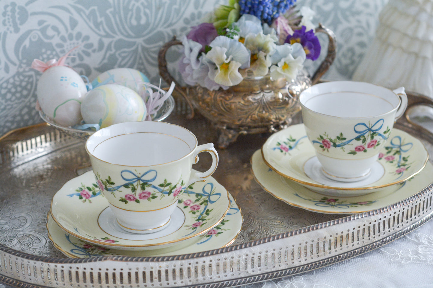 コルクラフ(Colclough)の可愛らしいティートリオ。コルクラフは1890年にハーバード・ジョセフ・コルクラフ氏が創業したメーカで、1940年代頃まで続いていました。コルクラフの中でもこのリボンの絵柄は人気で入手困難なお品です。クリーム色にブルーリボンと小さなバラの模様がとっても可愛らしいデザインです。パステルカラーがイースターや春のティータイムにもぴったりですね!