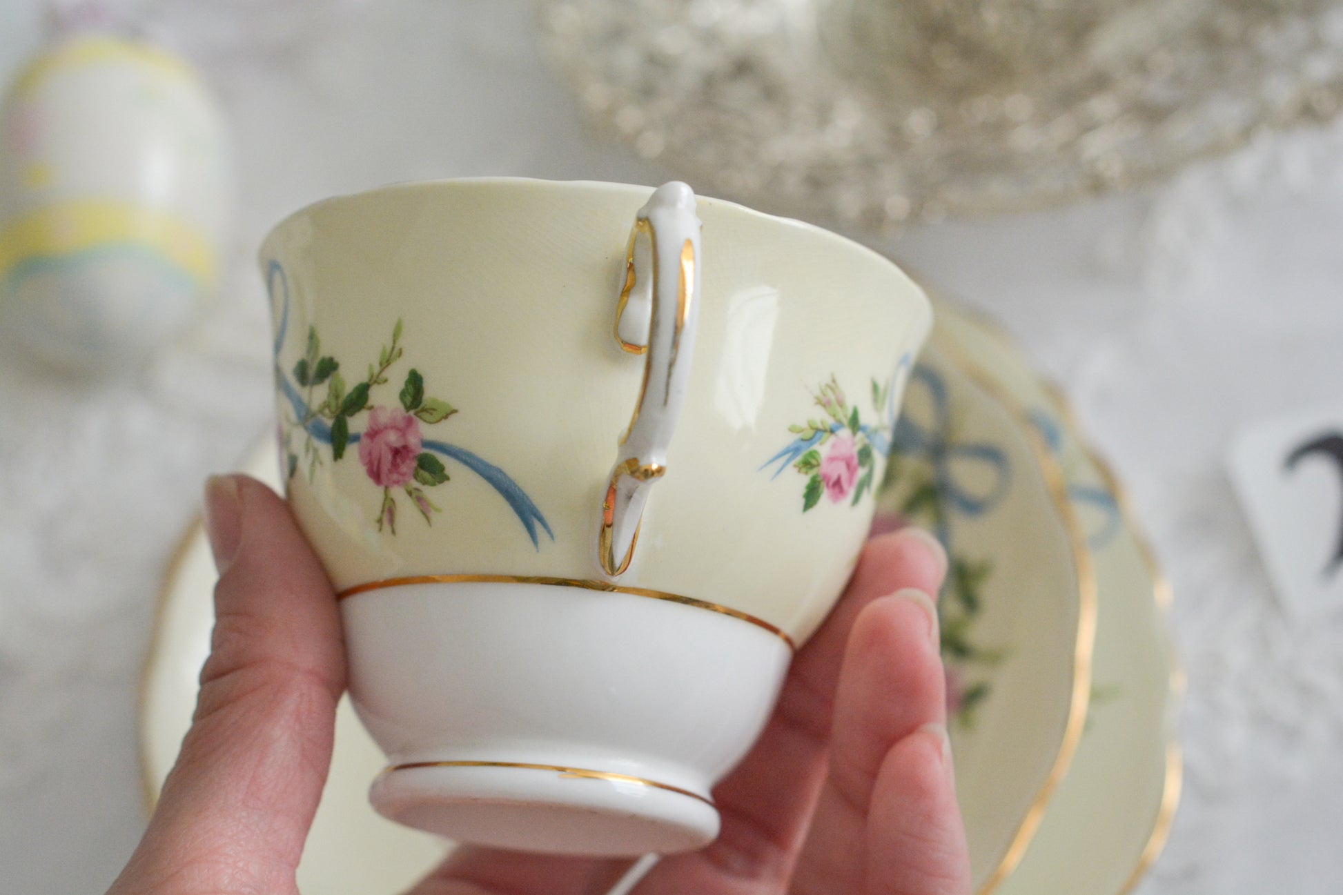 コルクラフ(Colclough)の可愛らしいティートリオ。コルクラフは1890年にハーバード・ジョセフ・コルクラフ氏が創業したメーカで、1940年代頃まで続いていました。コルクラフの中でもこのリボンの絵柄は人気で入手困難なお品です。クリーム色にブルーリボンと小さなバラの模様がとっても可愛らしいデザインです。パステルカラーがイースターや春のティータイムにもぴったりですね!