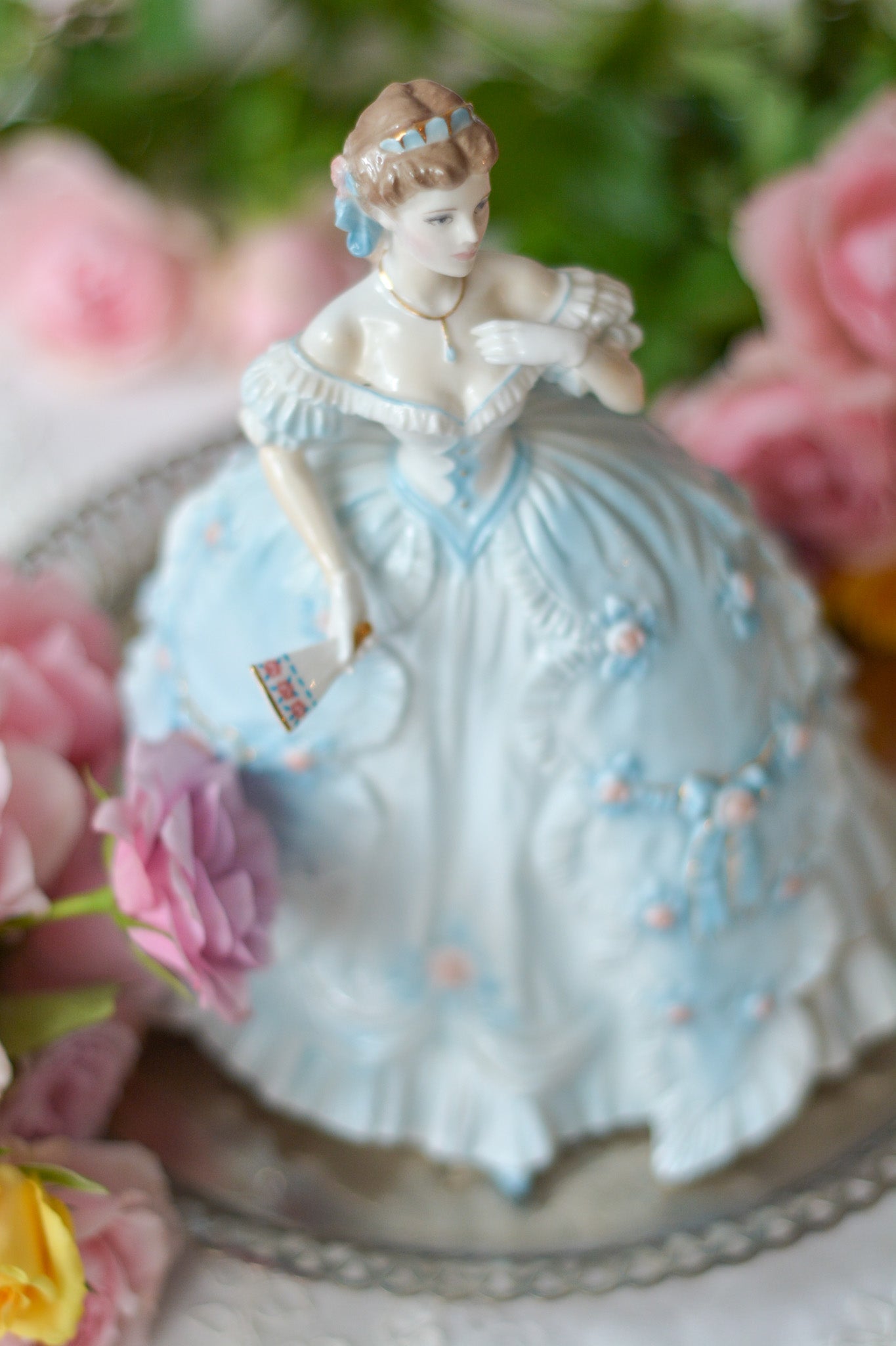 The First Quadrilleという題名のとても可愛らしいロイヤルウースターのフィギュリンです。フィギュリンの題名の通り「初めての舞踏会」に出たご令嬢がモデルになっています。可愛らしいお顔のお嬢様ですが、表情には少し緊張している様子がうまく表現されていると思いませんか?ドレスは爽やかな水色に大きなリボンと薔薇の花がたくさんついていて、舞踏会デビューを華やかに飾っています。とても可愛らしく、美しいフィギュリンでテーブルやお部屋に花を添えてくれます。