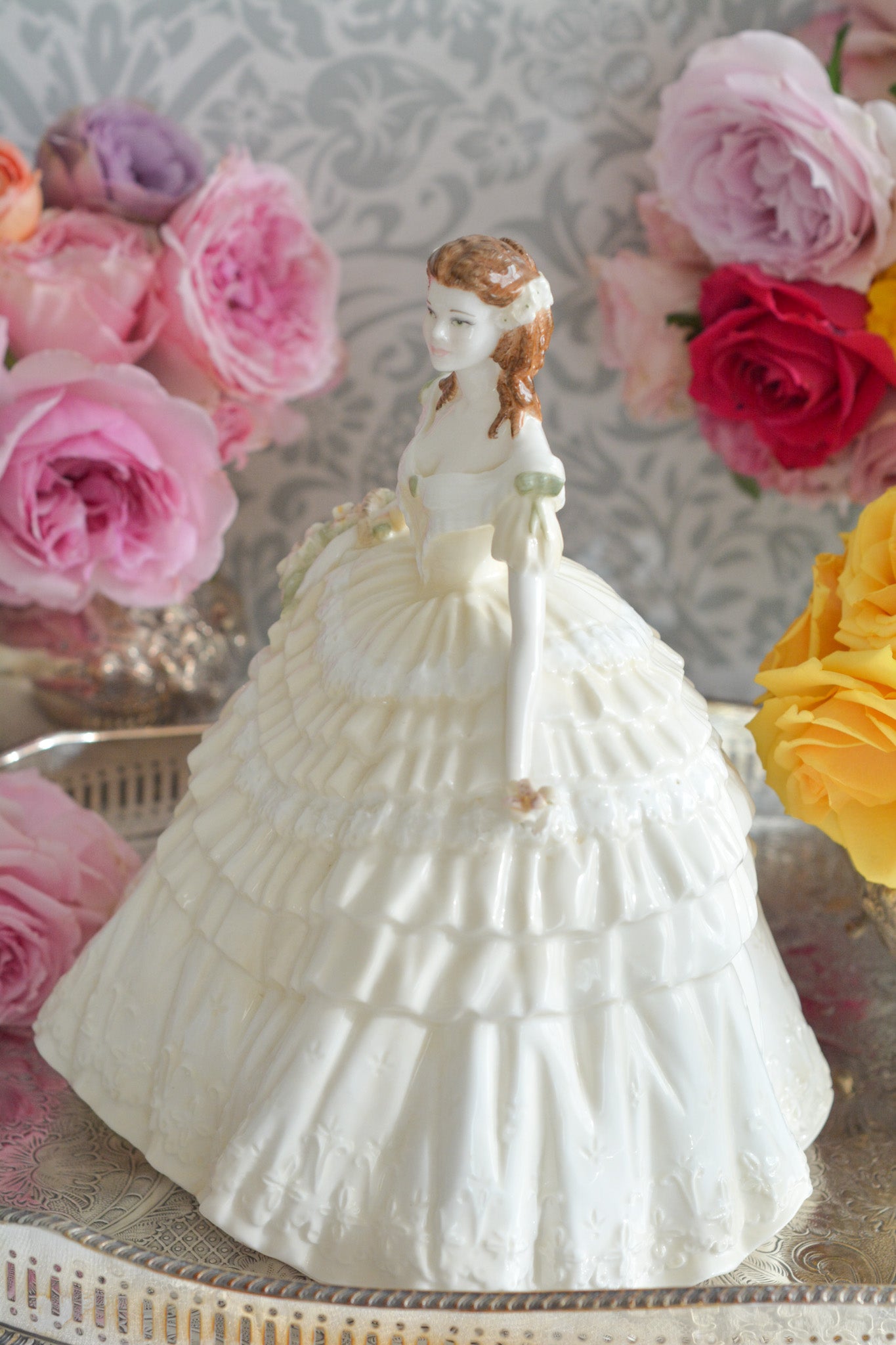 コールポートの人気フィギュリン、「The Four Flowers Collection」。名前の通り、「リリー、ローズ、カーネション、アイリス」の4つのお花がモチーフのフィギュリンシリーズです。 その中でも、リリーはアイリスと並び入手困難なお品です。  バスケットいっぱいのリリーと左手には一輪のリリーの花。ドレスはホワイトに淡いイエローのフリルとグリーンのリボンがあしらわれています。 柔らかな表情がとても可愛らしいレディのフィギュリンです。