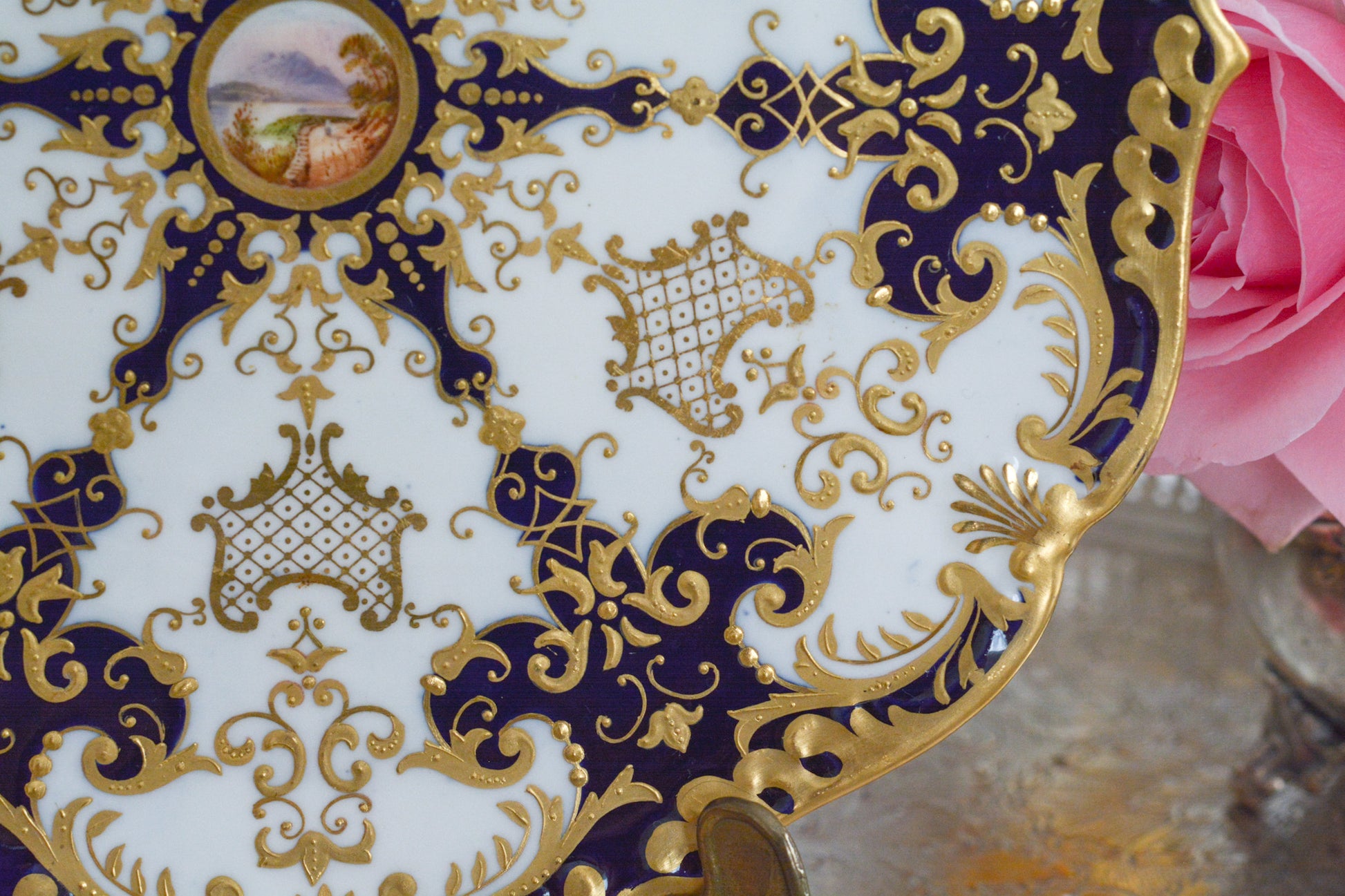 コールポートの大変美しいキャビネットプレート。豪華で繊細な模様に、中央には小さな風景画が描かれています。アンティークだからこその気品のあるデザイン。コールポートの逸品です。キャビネットプレートとして素晴らしい絵画の代わりにお部屋に飾っても素敵です。ぜひ宝物として受け継いでいただきたいです。 Rose Antiquesはコールポートをはじめ、英国アンティーク磁器、英国ヴィンテージ磁器、フィギュリン、アンティークシルバーをご紹介しています。 